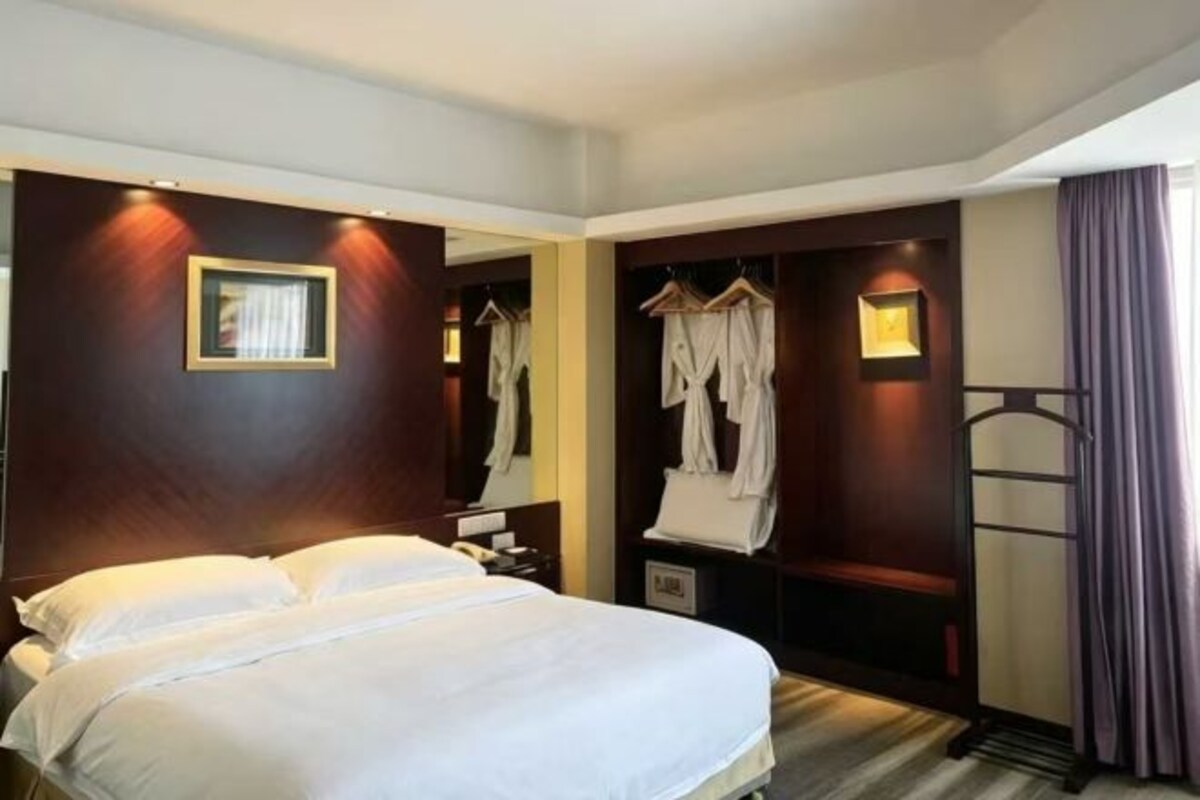 Una habitación de hotel con una cama, un armario y un espejo.