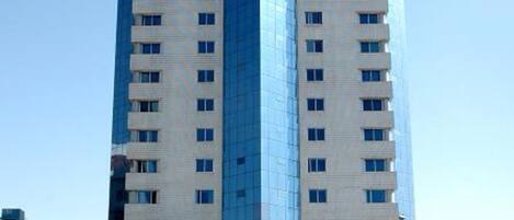Un grand immeuble d’hôtel au design moderne, avec de nombreux étages et une entrée imposante agrémentée d’une enseigne.