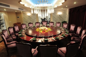 A round dining table with 12 chairs, a floral centerpiece, and a chandelier above. - Yinchuan Vintage Hill Hotels & Resorts (Yinchuan)