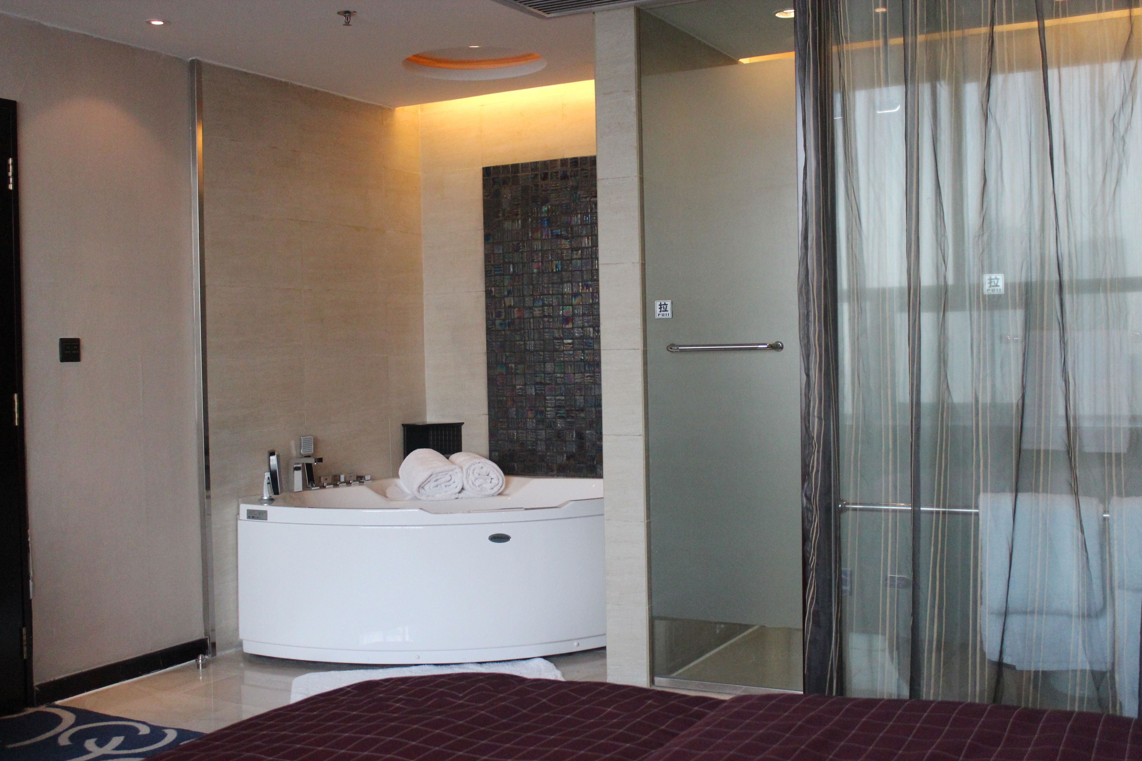 A modern bathroom with a bathtub, a glass shower enclosure, and a tiled wall.