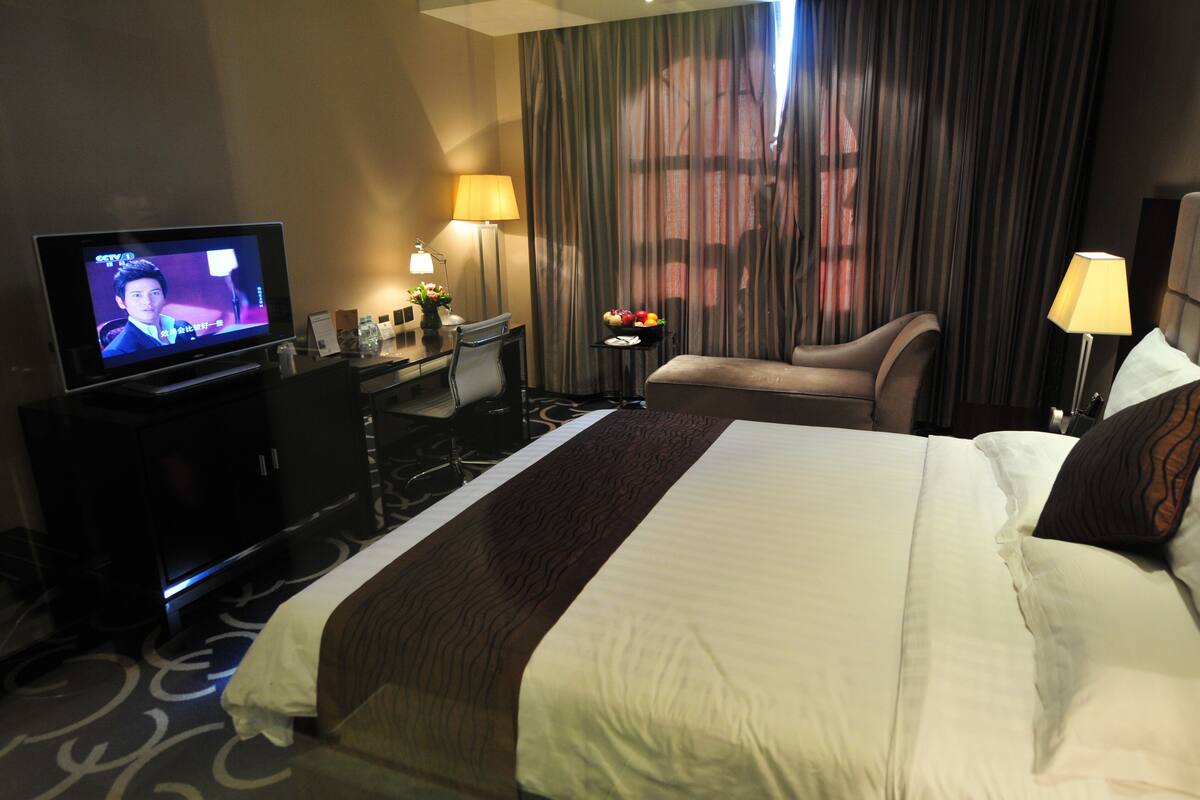 Ein Hotelzimmer mit Bett, Schreibtisch, Fernseher und Stuhl.
