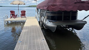 Un barco amarrado en un muelle con una zona de estar cubierta y dos sillas.