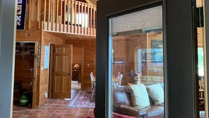 Un interior de madera con un cartel de 'WELCOME', una escalera, un comedor y una sala de estar con un sofá rosa.