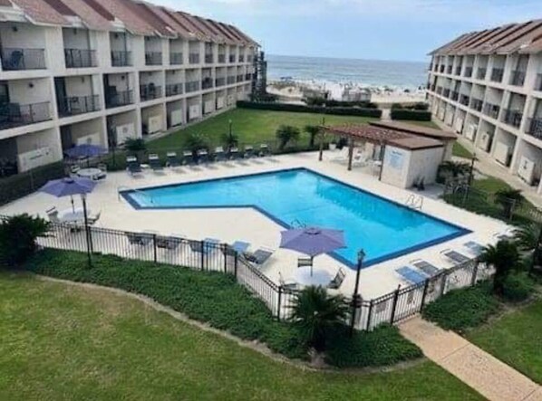 A hotel with a pool, multiple balconies, and a view of the beach.
