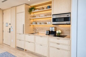 Una cocina moderna con armarios de madera, microondas integrado y cafetera.