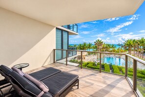A balcony with a pool view, lounge chairs, and a glass railing. - 4MM Oceanfront Residence- Finest Bal Harbour Resort by Guaranteed Rental™ (Bal Harbour)