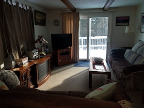 Ein Wohnzimmer mit Fernseher, Holzunterhaltungseinheit und einer Couch.