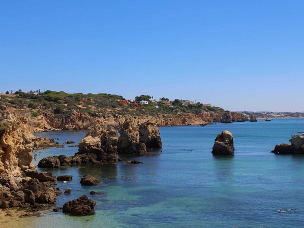 Paisagem costeira com formações rochosas e águas azul-claras.