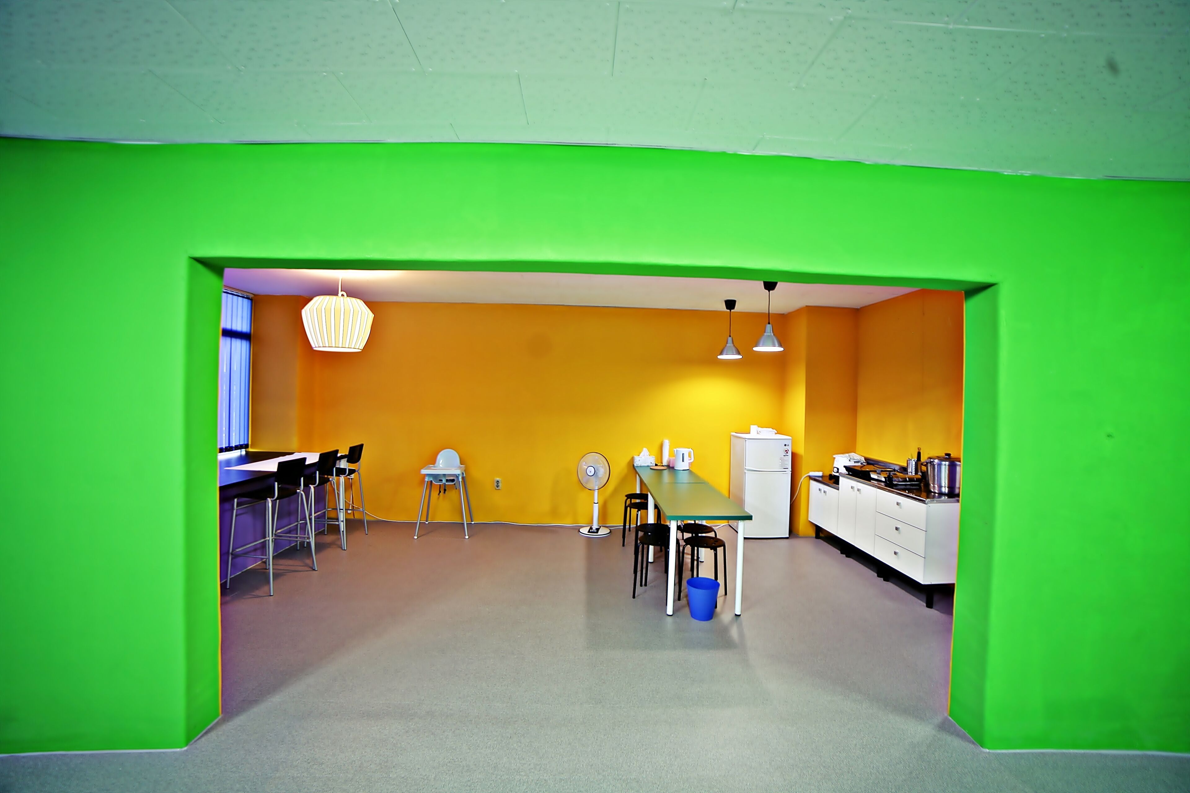 A bright kitchen with green walls, a dining area with chairs, and a white refrigerator.