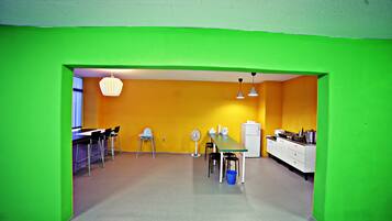 A bright kitchen with green walls, a dining area with chairs, and a white refrigerator.