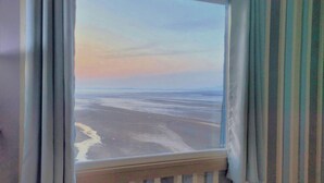 Una habitación con vista a la playa y al océano al atardecer.
