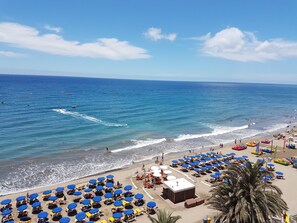 A beach with rows of sunbeds and umbrellas, a lifeguard tower, and a clear view of the ocean. - "Apartamento Milu' in Playa del Ingles de Gran Canaria ground floor. (San Bartolomé de Tirajana)