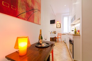 Uma cozinha moderna com área de jantar, uma mesa com champanhe e copos, uma TV na parede e um quadro sobre a mesa.