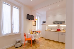 Uma cozinha compacta com mesa de jantar, cadeiras e uma TV fixada acima.