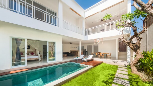 Una casa moderna de dos pisos con piscina, comedor y balcón.