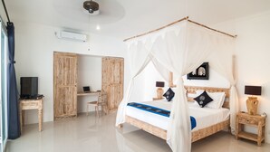 Un dormitorio con cama con dosel, un escritorio, una silla y un televisor.