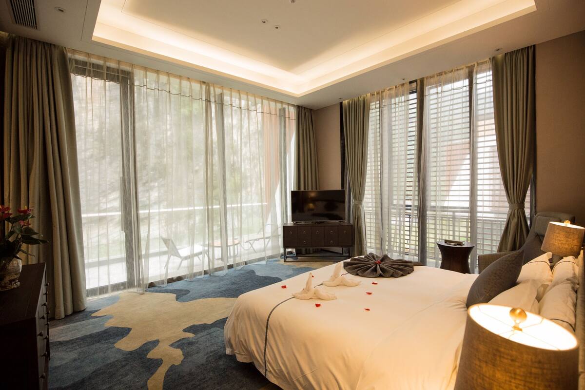 Ein Hotelzimmer mit einem großen Bett, einem Fernseher, einem Schreibtisch und einem Sessel.