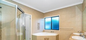 A modern bathroom with a glass shower enclosure, a large window, and two sinks.