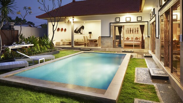 Uma piscina com área de terraço, espaço coberto para sentar e gramado bem cuidado.