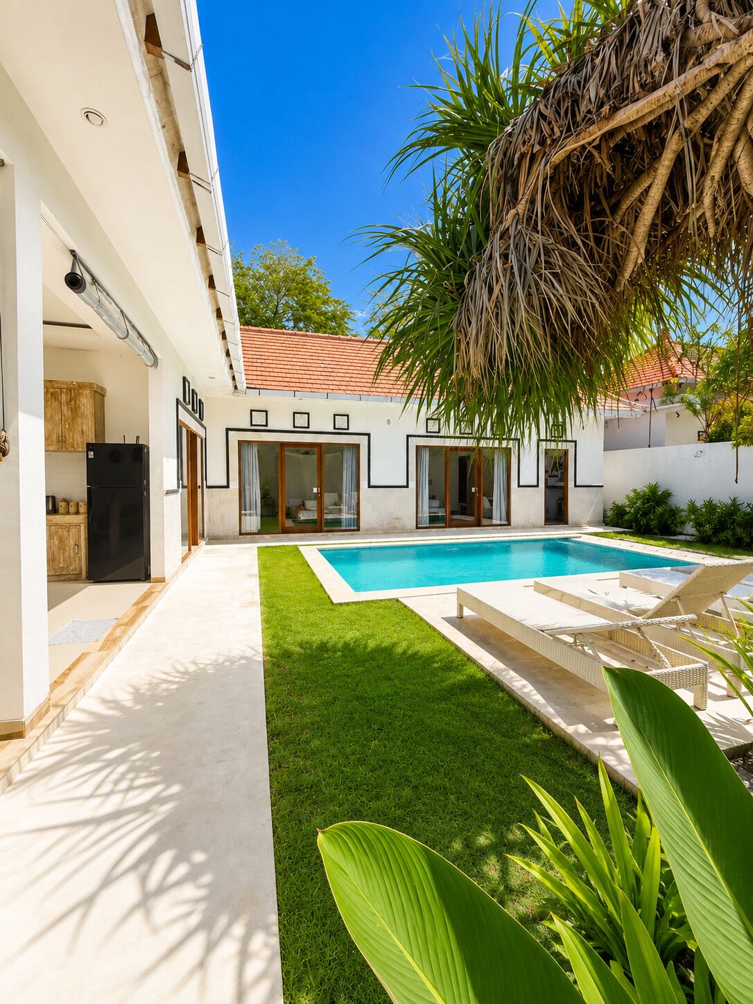 A modern house with a swimming pool, a covered patio, and a well-maintained lawn.