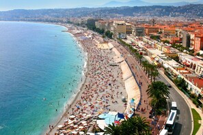 A coastal cityscape with a wide beach, a promenade lined with buildings, and a clear view of the sea.