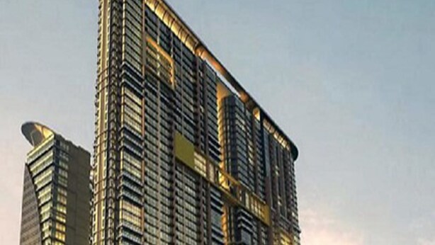 Un hotel moderno de gran altura con fachada curva, varios balcones y vista al agua.