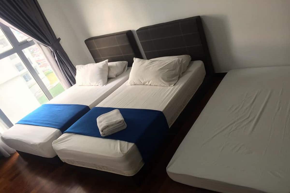 A hotel room with two single beds and a larger bed.