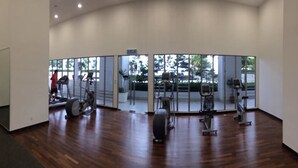 Un gimnasio con equipamiento de ejercicio, ventanas amplias y suelo de madera.