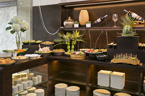 Un buffet proposant une variété de plats, des assiettes et un choix de vins.