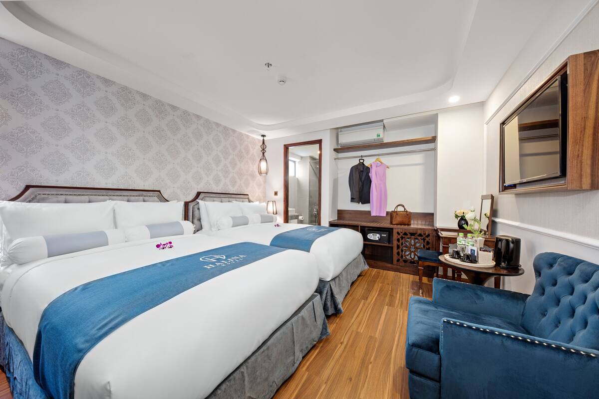 A hotel room with a large bed, a desk, a chair, and a mirror.