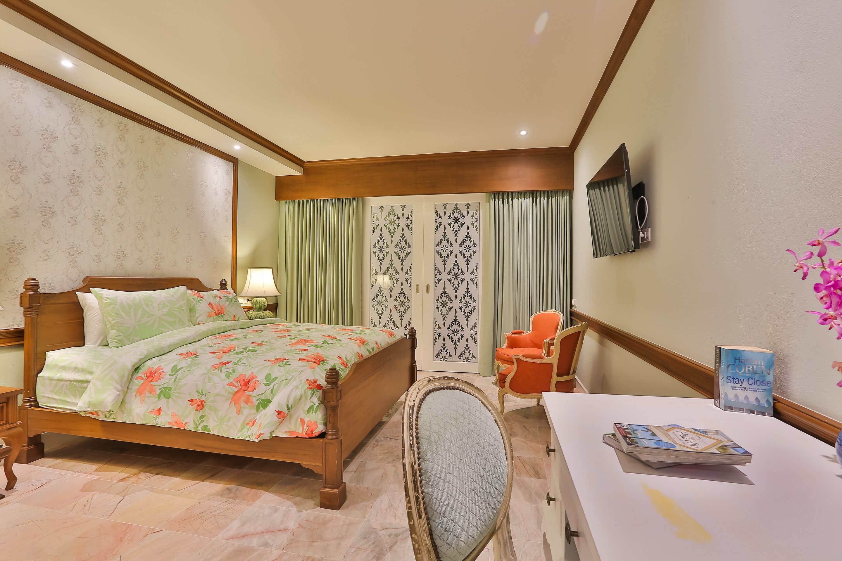 A hotel room with a wooden bed, a desk with a chair, a television, and a sign on the wall.