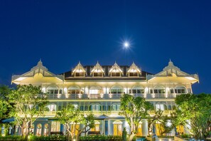 A large, ornate building with multiple balconies and a prominent central tower, surrounded by lush greenery. - At Pingnakorn Riverside Hotel Chiangmai (Chiang Mai)