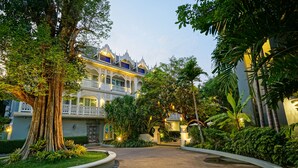 A large, ornate building with a grand entrance, surrounded by lush greenery and a well-maintained garden. - At Pingnakorn Riverside Hotel Chiangmai (Chiang Mai)