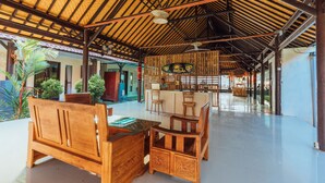 A spacious indoor area with a high ceiling and a thatched roof structure. There are wooden furniture pieces and a bar area with stools. - Semaya One Beach Guesthouse (Penida Island)