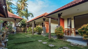 A courtyard with a tiled roof, palm trees, and a seating area with chairs. - Semaya One Beach Guesthouse (Penida Island)