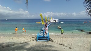 A beach with a blue jetty leading to a boat. - Semaya One Beach Guesthouse (Penida Island)