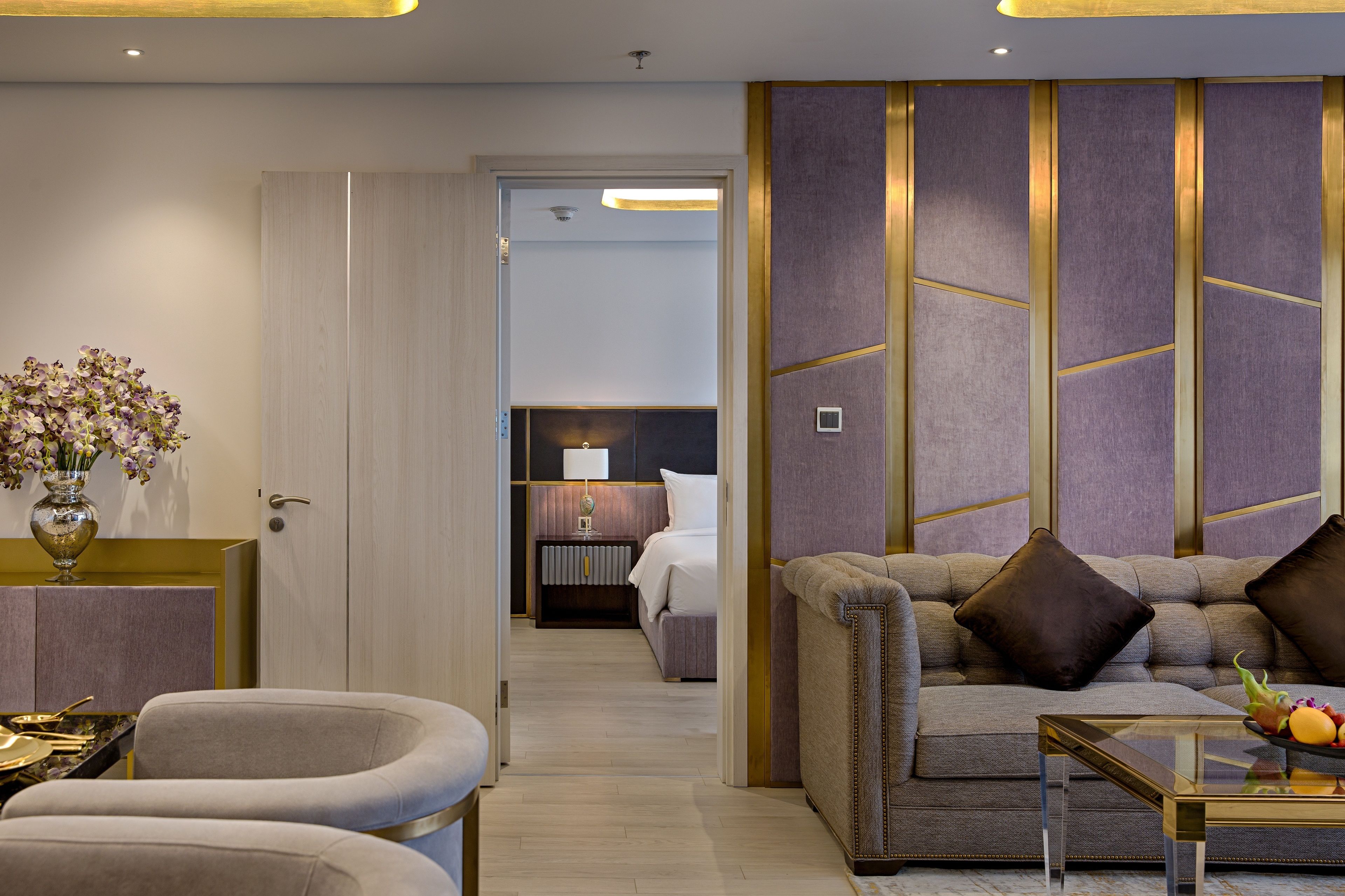 Una habitación de hotel moderna con un sofá, una mesa de centro de cristal y un jarrón con flores.