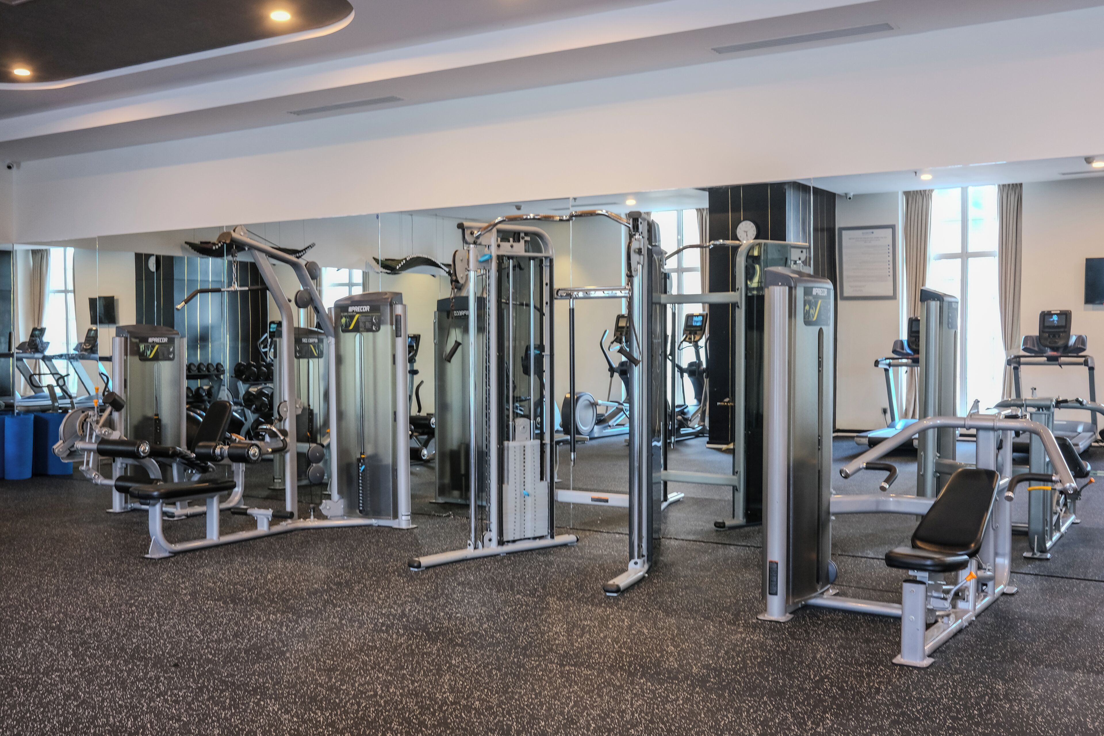 Ett gym med olika träningsmaskiner, speglar och ett golv täckt med matta.