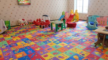 Children can play and learn on the colorful foam mat floor, surrounded by toys and a TV for entertainment.