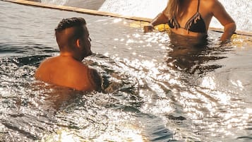 A person in a swimming pool with a bridge in the background.