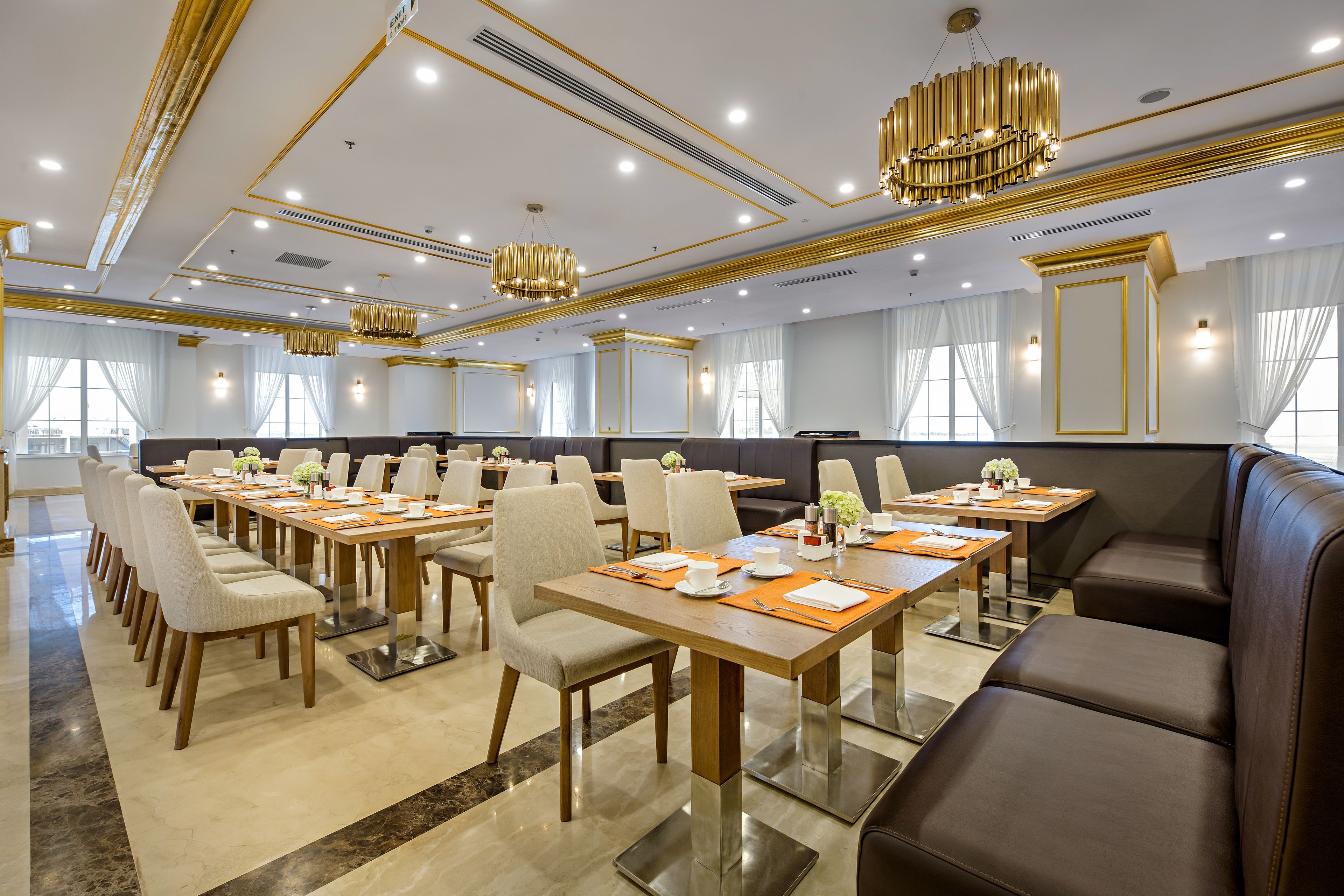 A conference room with multiple tables and chairs, a large seating area, and modern chandeliers.