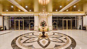 A grand lobby with a marble floor, a central chandelier, and a floral arrangement. - Wyndham Danang Golden Bay (Da Nang)