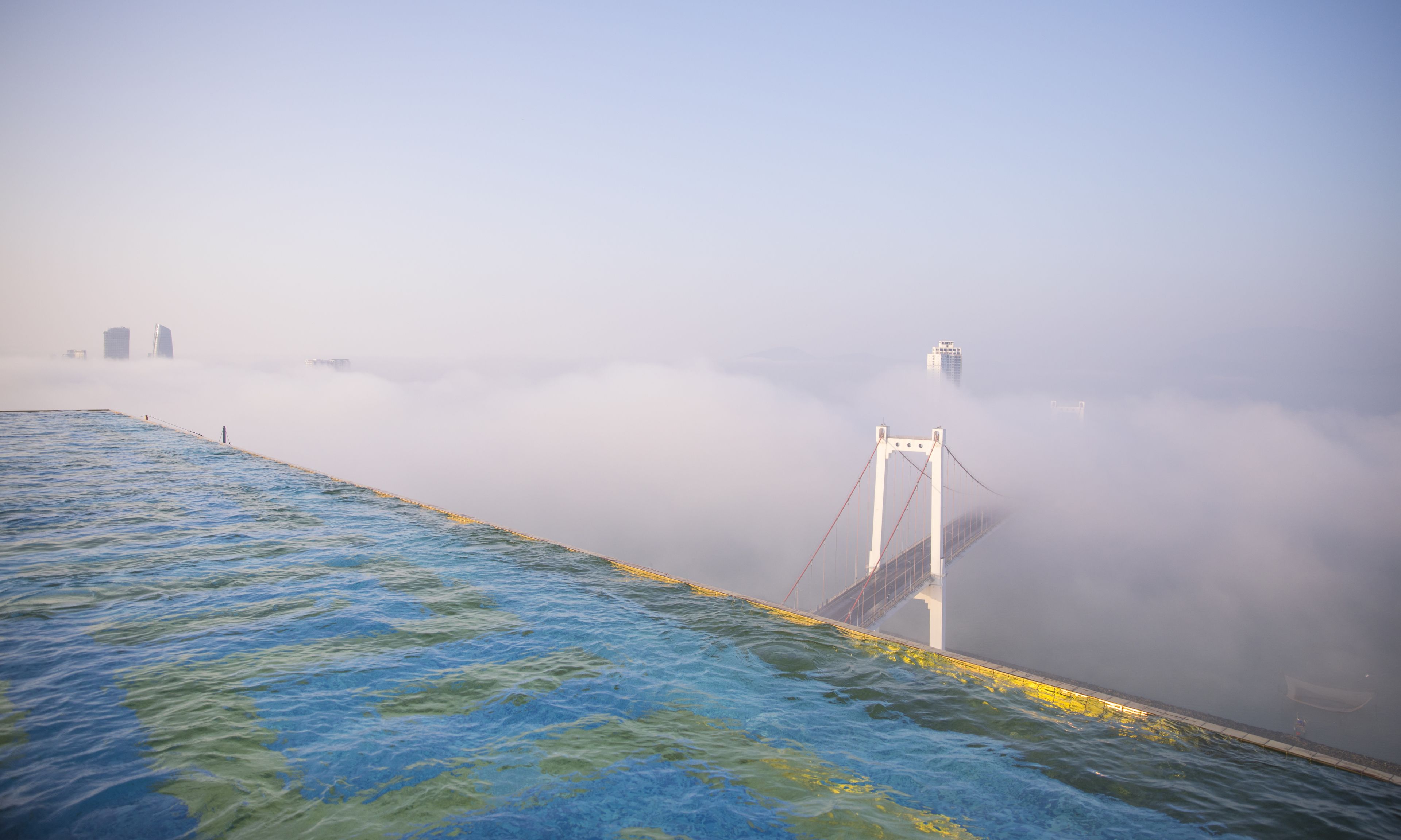 Un pont se détachant sur un arrière-plan brumeux, avec une étendue d'eau au premier plan.