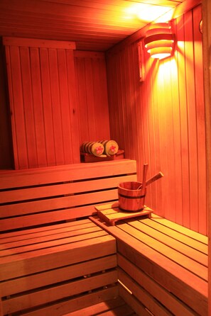 A wooden sauna with benches and a bucket with a brush.
