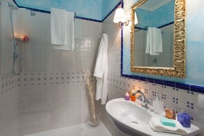 A bathroom with a shower, a sink with toiletries, and a mirror with a decorative frame. - La Culla di Dante Luxury Apartment in front of the Duomo (sleeps 6) (Firenze)