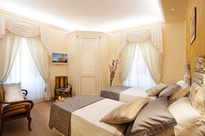 Habitación de hotel con dos camas, una silla, una mesita y un cuadro en la pared.