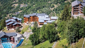 Una località montana con diversi edifici, tra cui un ampio hotel con balconi e una zona piscina.