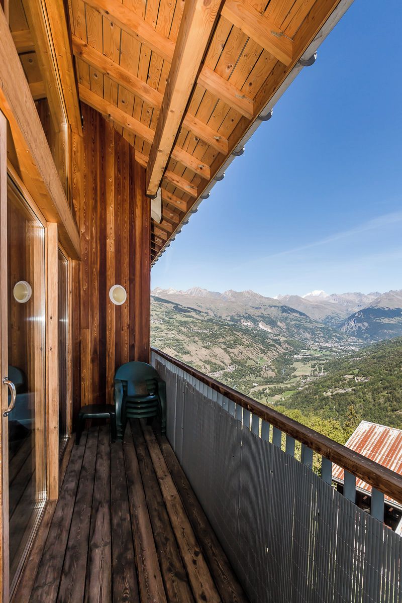 A wooden balcony with a view of a mountainous landscape.