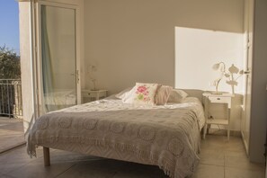 A bedroom with a bed, a nightstand, a dresser, and a sliding glass door leading to an outdoor area.