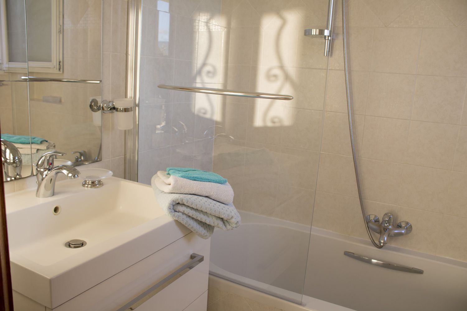 A bathroom with a bathtub, a sink, and a mirror.